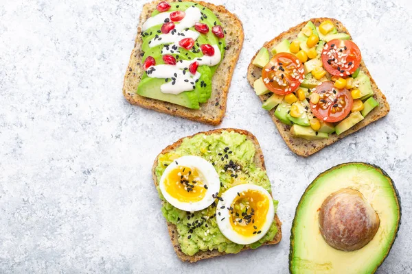 Yumurta, domates, baharat ve beyaz taş zemin üzerine bütün avokado Yarım avokado tost. Sağlıklı kahvaltı avokado sandviç farklı soslar, üstten görünüm, yakın-u