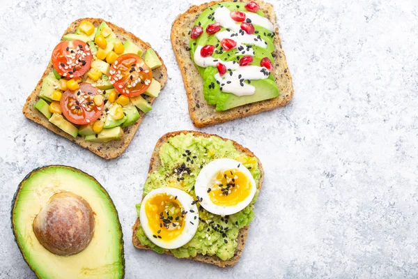 Yumurta, domates, baharat ve beyaz taş zemin üzerine bütün avokado Yarım avokado tost. Sağlıklı kahvaltı avokado sandviç farklı soslar, üstten görünüm, yakın-u