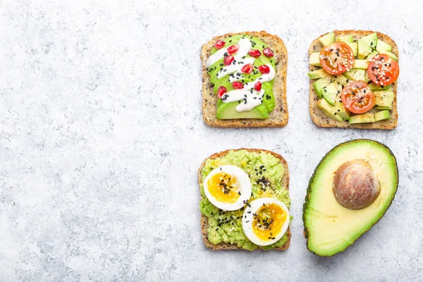 Yumurta, domates, baharat ve beyaz taş arka plan, metin için yer üzerinden tüm avokado yarısını avokado tost. Sağlıklı kahvaltı avokado sandviç farklı soslar, üstten görünüm, yakın-u