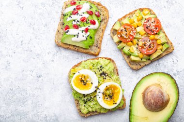 Yumurta, domates, baharat ve beyaz taş zemin üzerine bütün avokado Yarım avokado tost. Sağlıklı kahvaltı avokado sandviç farklı soslar, üstten görünüm, yakın-u