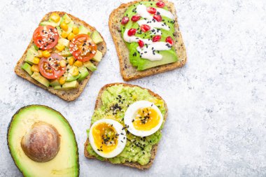Yumurta, domates, baharat ve beyaz taş zemin üzerine bütün avokado Yarım avokado tost. Sağlıklı kahvaltı avokado sandviç farklı soslar, üstten görünüm, yakın-u