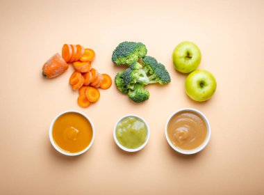 İle sağlıklı doğal bebek maması pastel arka plan üzerinde beyaz kase. Taze organik meyve ve sebze, püreler, flay yatıyordu, en iyi görünüm, kavram. Yapılan havuç, brokoli, elma çocuklar için gıda 