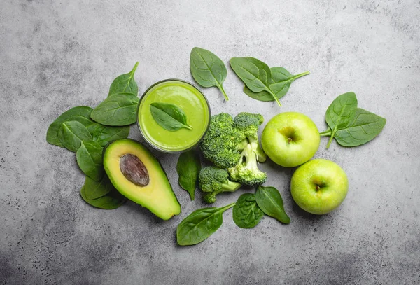 Ingredients for making green healthy smoothie, broccoli, apples, avocado, spinach over gray stone background. Clean eating, detox plan, vitamins, diet and weight loss concept. Close up, top view
