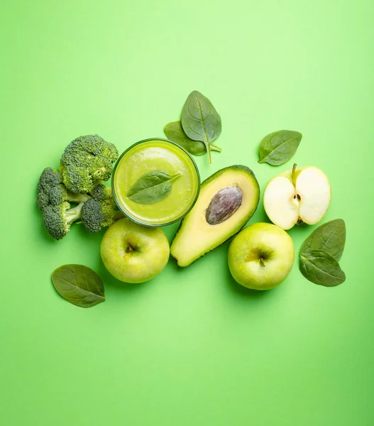 Ingredients for making green healthy smoothie with broccoli, apples, avocado, spinach on green pastel background. Clean eating, detox plan, diet, weight loss concept. Close up, top view