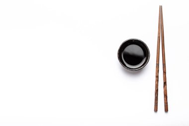 Soya sosu ve metin alanı olan beyaz arka plan üzerinde ahşap çubuk ile küçük rustik kase. Suşi restoranı, Japon mutfağı veya menü şablonu, üstten görünüm kavramı 