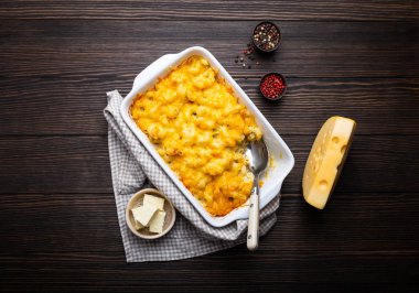 Fırında makarna ve peynir, baharat, tereyağı, kaşık ve çatal, üstten görünüm rustik ahşap zemin üzerine beyaz güveç içinde Close-up. Peynirli soslu makarna, İngilizce/gıda konfor. 