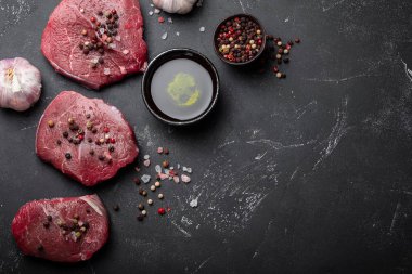 Yakın çekim çiğ taze mermer et Steak tuz ve biber, zeytin yağı karanlık rustik beton zemin üzerine sarımsak hazır ti pişmiş olabilir. Metin, en iyi görünüm için yer konseptiyle et pişirme