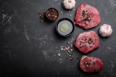 Yakın çekim çiğ taze mermer et Steak tuz ve biber, zeytin yağı karanlık rustik beton zemin üzerine sarımsak hazır ti pişmiş olabilir. Metin, en iyi görünüm için yer konseptiyle et pişirme