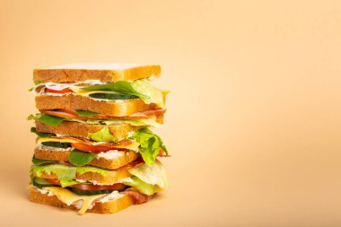 Uzun boylu bütün lezzetli sandviç ile peynir, jambon, salam, taze marul, domates, salatalık pastel Sarı zemin üzerine kapatın. Sağlıklı gurme sandviç kahvaltı ve öğle yemeği için. Metin için yer 