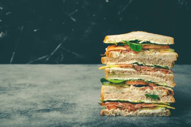 Uzun kesme lezzetli sandviç ile peynir, jambon, salam, taze marul, domates, salatalık gri rustik taş zemin üzerine kapatın. Sağlıklı gurme sandviç kahvaltı ve Öğle Yemeği, metin için yer için