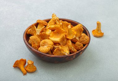 Kırsal ahşap bir kasede taze chanterelle mantarları, gri bir arka planda, sıcak ve davetkar bir sonbahar sahnesi mutfak için mükemmel.