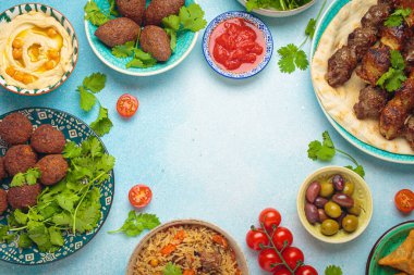 Orta doğu ya da Arap yemeklerinin çerçeve kompozisyonu ve açık bej arka planda çeşitli mezeler. Et kebabı, falafel, humus, sambusak, pilav, kibbe, pide. Kutsal yiyecekler. Lübnan mutfağı, kopyalama alanı