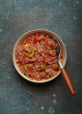 Geleneksel bir Küba yemeği olan Ropa vieja, yukarıdan koyu kırsal arka planda bir tabakta beyaz pirinç, domates sosu ve yeşil zeytin ile servis edilir.