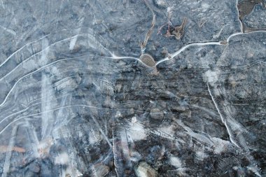 Çakıl taşları buz kabuğundan görülebilir. Su birikintisindeki ilk buz tabakasının altında çakıl taşları görülebilir. Su birikintisindeki ilk ince buz tabakası, şeffaf ve narin..