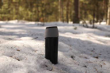 Termos karların içinde. Ormanda termos ilkbahar karında duruyor. Sibirya ormanında sıcak çay eşliğinde güzel bir termo bardak..