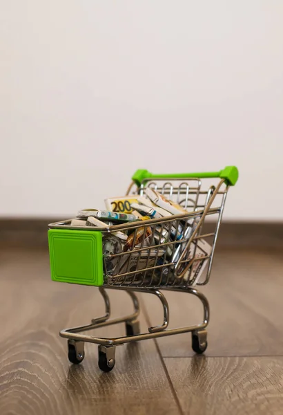 Mini basket filled with sweets in the form of money. Money basket. Small cart full of money. The cart is loaded with sweets. Trolley with cash candy.