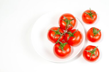 Beyaz arka planda sığ bir tabakta kırmızı domatesler. yakın plan