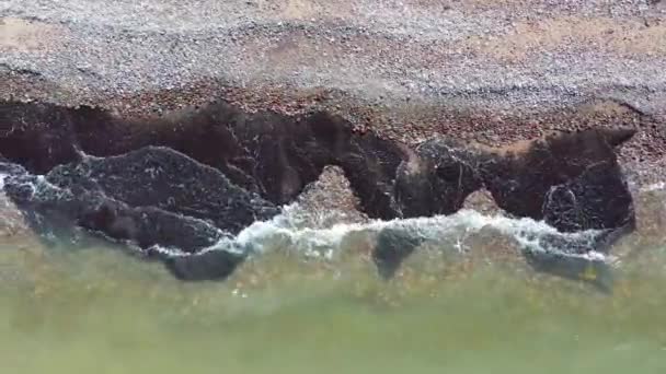 Aerial shot flying along shoreline. Waves crashing against pebble beach — Stock Video