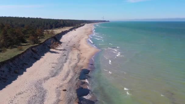 Vista aérea voando ao longo da costa litorânea litorânea do mar Báltico letão em direção à turbina eólica perto de Liepaja — Vídeo de Stock