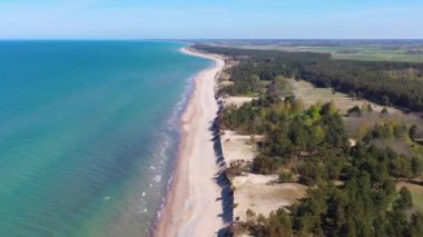 Liepaja yakınlarındaki rüzgar türbinine doğru Letonya Baltık Denizi kıyısı boyunca uçan hava manzarası