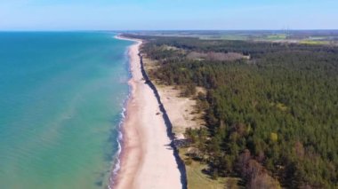 Liepaja yakınlarındaki rüzgar türbinine doğru Letonya Baltık Denizi kıyısı boyunca uçan hava manzarası