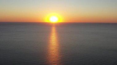 Güzel gün batımına doğru denize uçuyor. Deniz yüzeyinde gün batımı dalgalarla, hava görüntüleriyle.