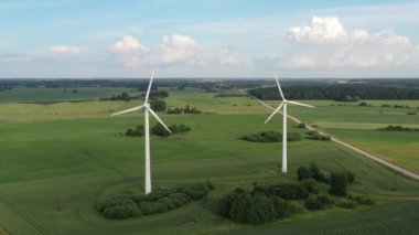 Yeşil alanda dönen rüzgar türbinlerine doğru uçan hava çekimi.