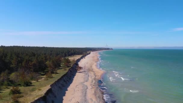 Vista aérea ascendente ao longo da costa litorânea do mar Báltico da Letónia revelando turbina eólica perto de Liepaja — Vídeo de Stock