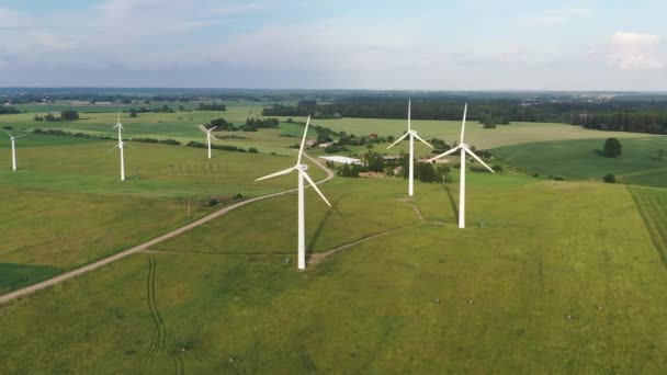 Disparo aéreo volando hacia turbinas eólicas giratorias en campo verde — Vídeos de Stock