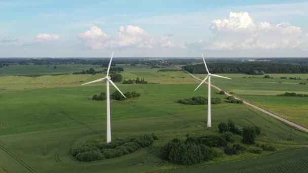Tiro aéreo voando em direção a turbinas eólicas rotativas em campo verde — Vídeo de Stock