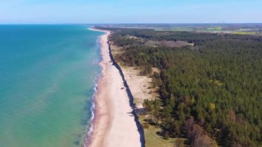 Liepaja yakınlarındaki rüzgar türbinine doğru Letonya Baltık Denizi kıyısı boyunca uçan hava manzarası