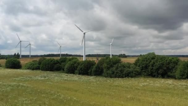 Disparo aéreo ascendiendo y volando hacia aerogeneradores giratorios en campo verde. Cielo nublado — Vídeos de Stock