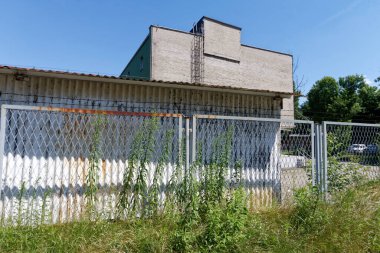 Çitin arkasındaki eski tuğla depo.