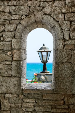 Kolaj bilgisayar görüntüsü taş savaş kulesi penceresi ve deniz, lamba ve turuncu çiçekler manzaralı