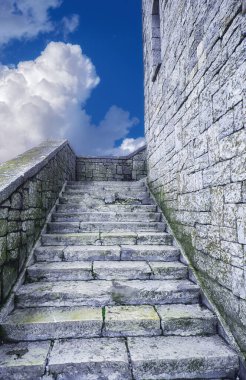 Savaş kulesinin tepesine giden antik taş merdivenler ve cennet bulutları.