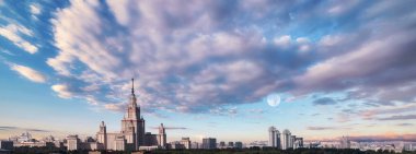 Günbatımında Moskova 'da eski üniversitenin ana binası ve kampüs parkının üzerinde dramatik bulutlu gökyüzü panoramik açıdan geniş açı 