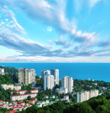 Soçi şehri yakınlarındaki Karadeniz 'in mavi sahili, güneşli yaz aylarında dramatik bulutlu gökyüzü altında konut evleri ve dinlenme alanı.