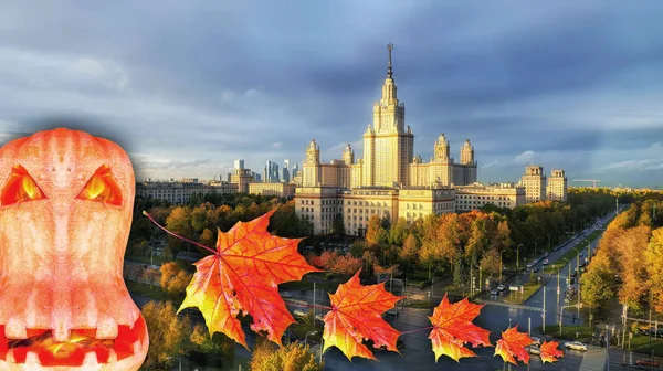 Halloween pumpkin and flying maple leaves on background of famous Russian university campus in Moscow under dramatic sky in autumn