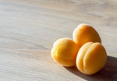 Ahşap bir arka planda arka planda üç kayısı.