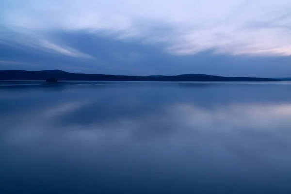 Красивые облака в голубой час над озером — стоковое фото