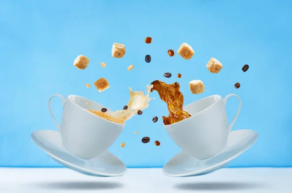 Flying cups of coffee with sugar and coffee beans on a blue background. toning. selective focus