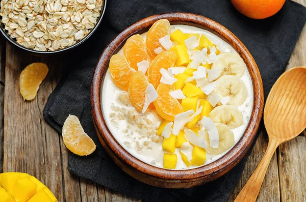 Oatmeal with mango, banana, tangerine oranges and coconut flakes. toning. selective focus