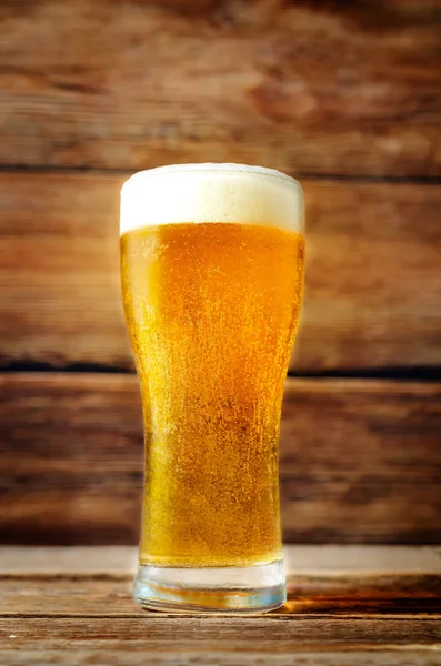 Glass of cold light beer on a wood  background. toning. selective focus