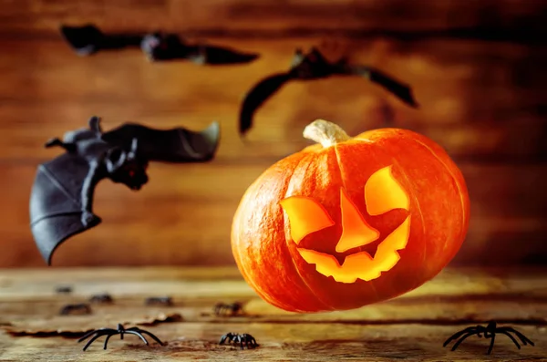 Flying glowing pumpkin with bats on dark wood background. Halloween concept. Toning. Selective focus