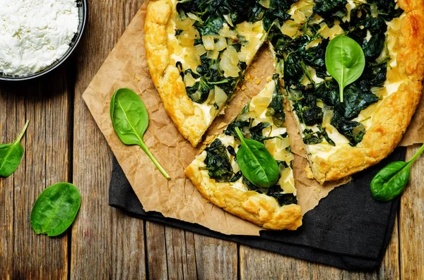 Spinach Ricotta Galette with fresh spinach leaves on a wood back