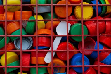 RIO GALLEGOS, ARGENTINA - 23 Eylül 2020: metal bir çitin içinden geri dönüşüm için etrafında birçok renkli şişe kapağı bulunan plastik bir kaşık