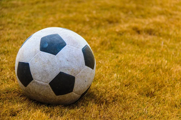 Dirty soccer ball on grass background