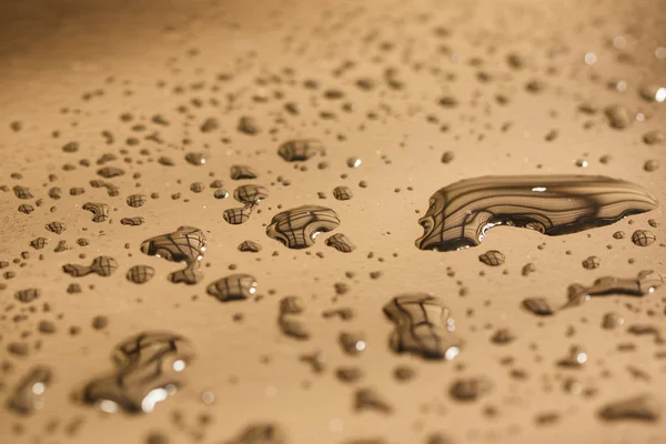 Pattern of water drops in a shiny metallic surface with table reflections