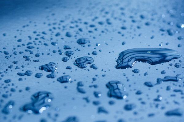 Капли воды на блестящей металлической поверхности с отражениями стола
