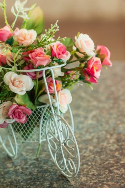 Mermer masa üzerinde beyaz bisiklet sepetinde yapay çiçekler